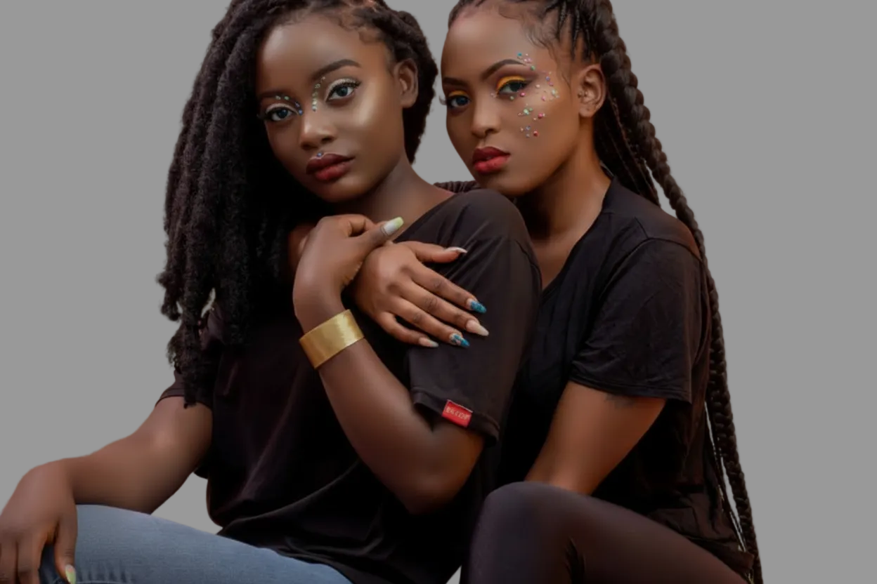 Two women sitting together against a pink background